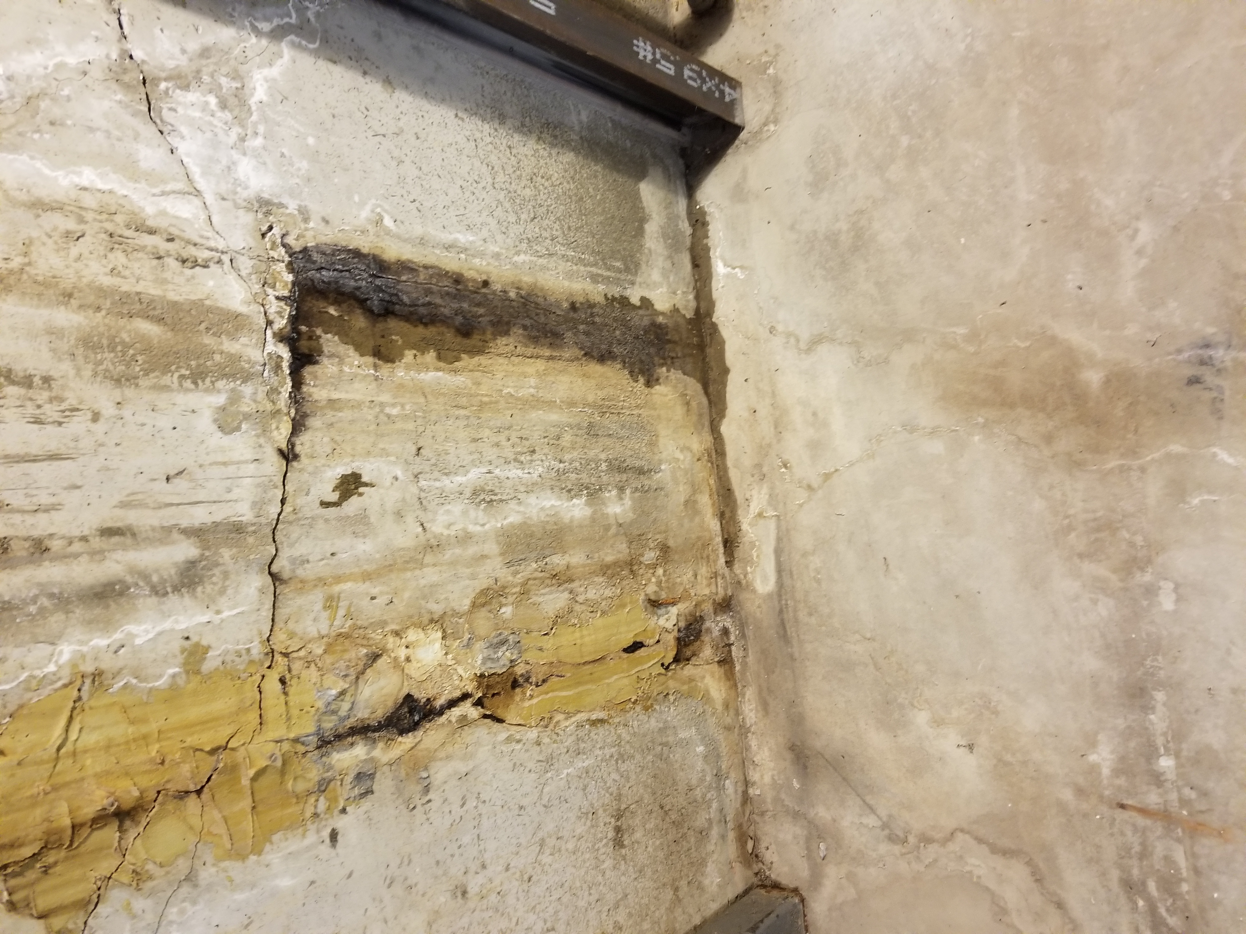 Poured concrete wall showing cracks and water damage before waterproofing — Beaverdale, Des Moines, IA