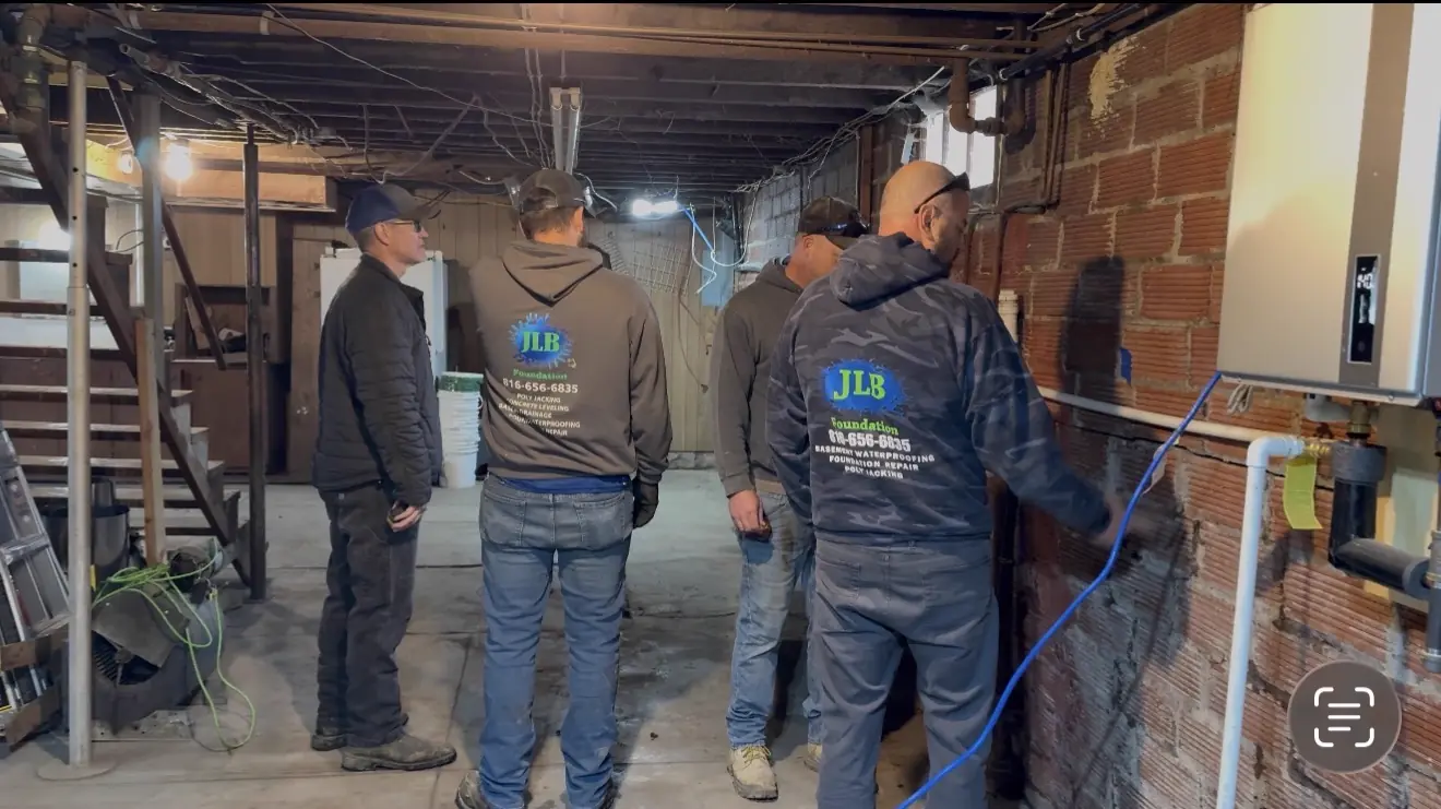 JLB crew discussing waterproofing plan in basement — Liberty, Missouri