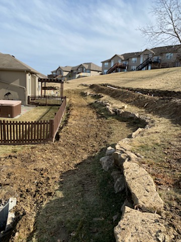 Hillside drainage trench excavation behind subdivision homes — Lee's Summit, MO