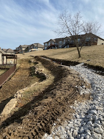Riprap and gravel being placed in drainage swale — Lee's Summit, MO