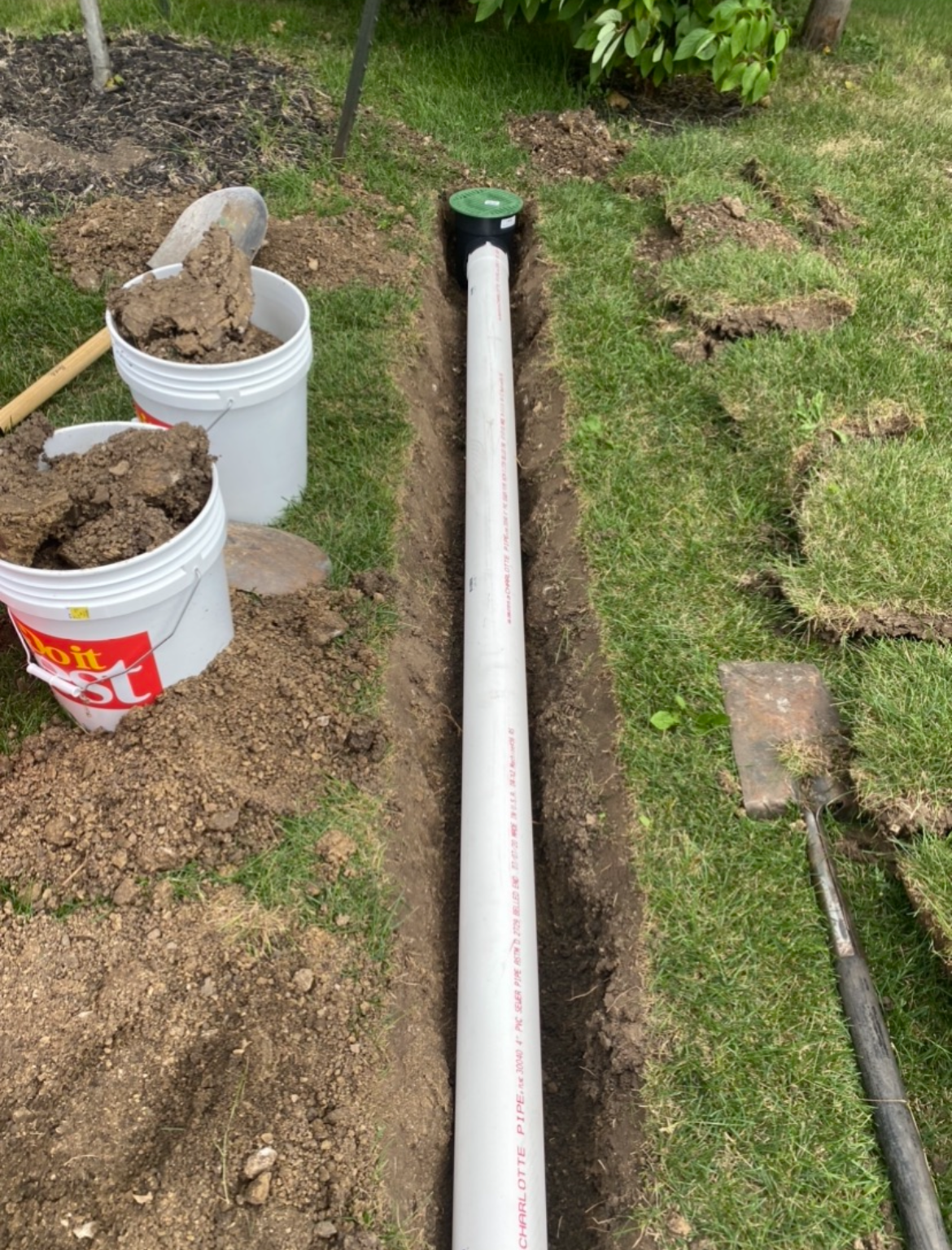 Downspout extension drain pipe being laid in trench — Urbandale, IA
