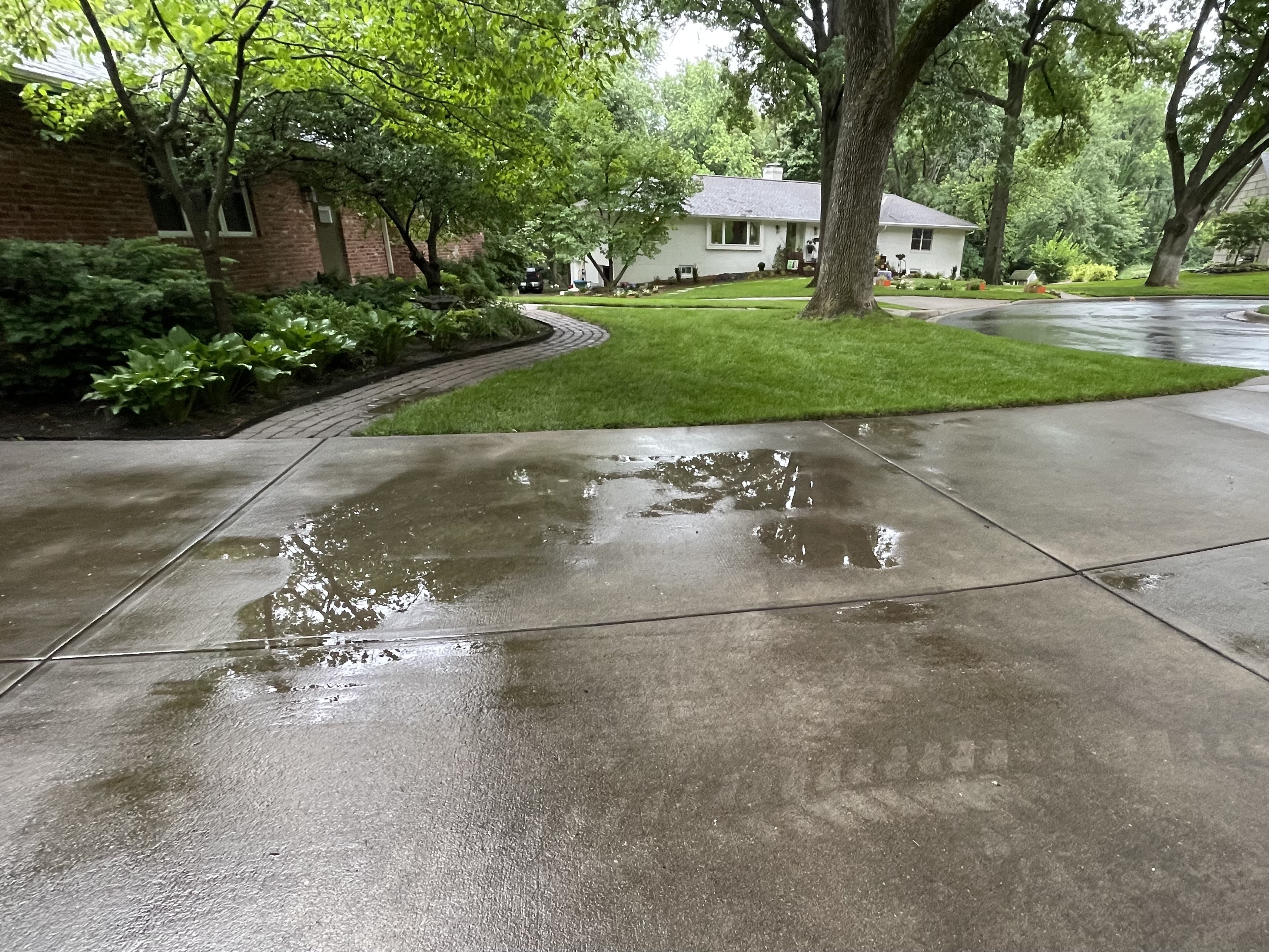 Standing water on driveway surface showing settlement — Leawood, KS