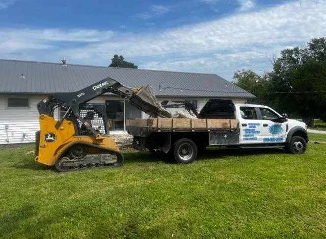JLB flatbed truck and compact track loader on a lawn