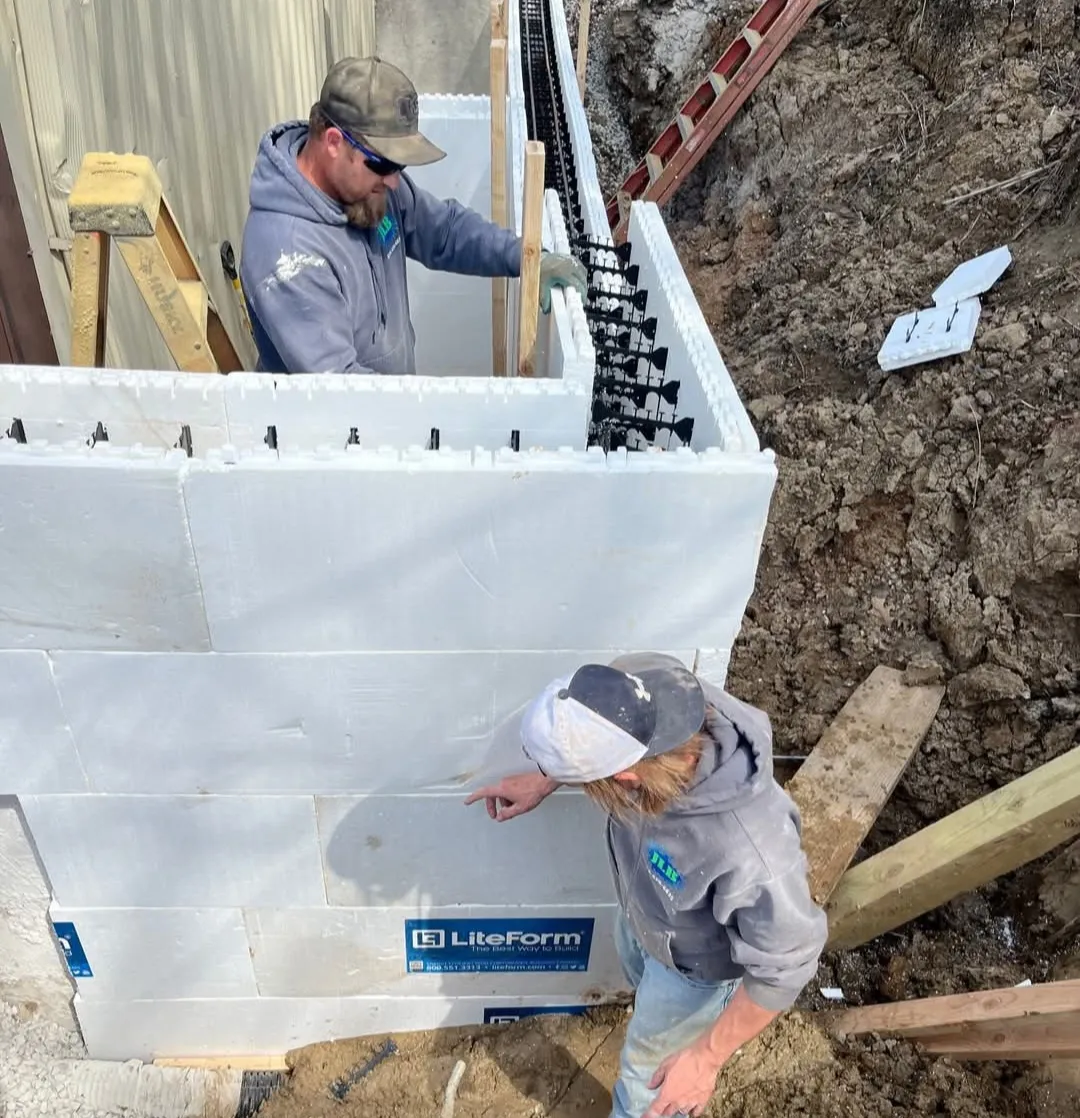Two JLB Foundation Repair specialists at work on Van Meter, IA home foundation