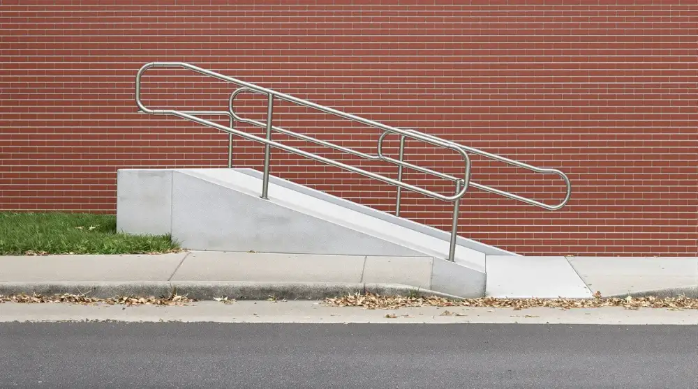 Concrete ADA ramp with handrail at a brick entrance — ada ramps by JLB in Ames, Iowa