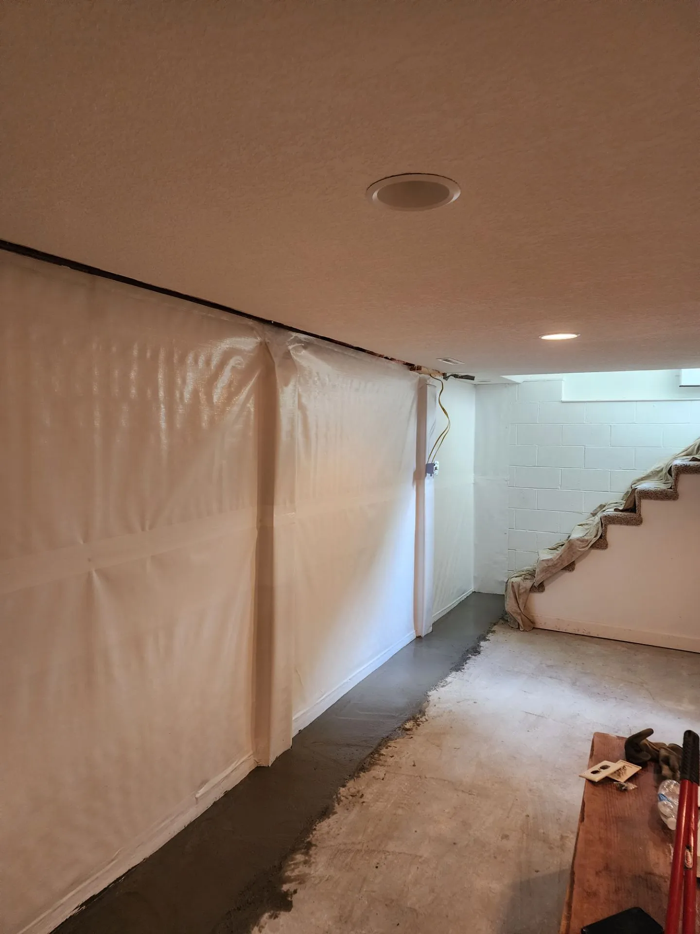 Interior waterproofing membrane system installed on basement block wall near stairs in Kansas City, MO